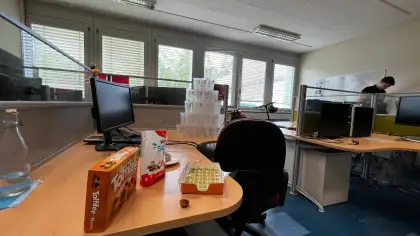 My desk at CERN with chocolates on it and a pyramid of paper cups behind